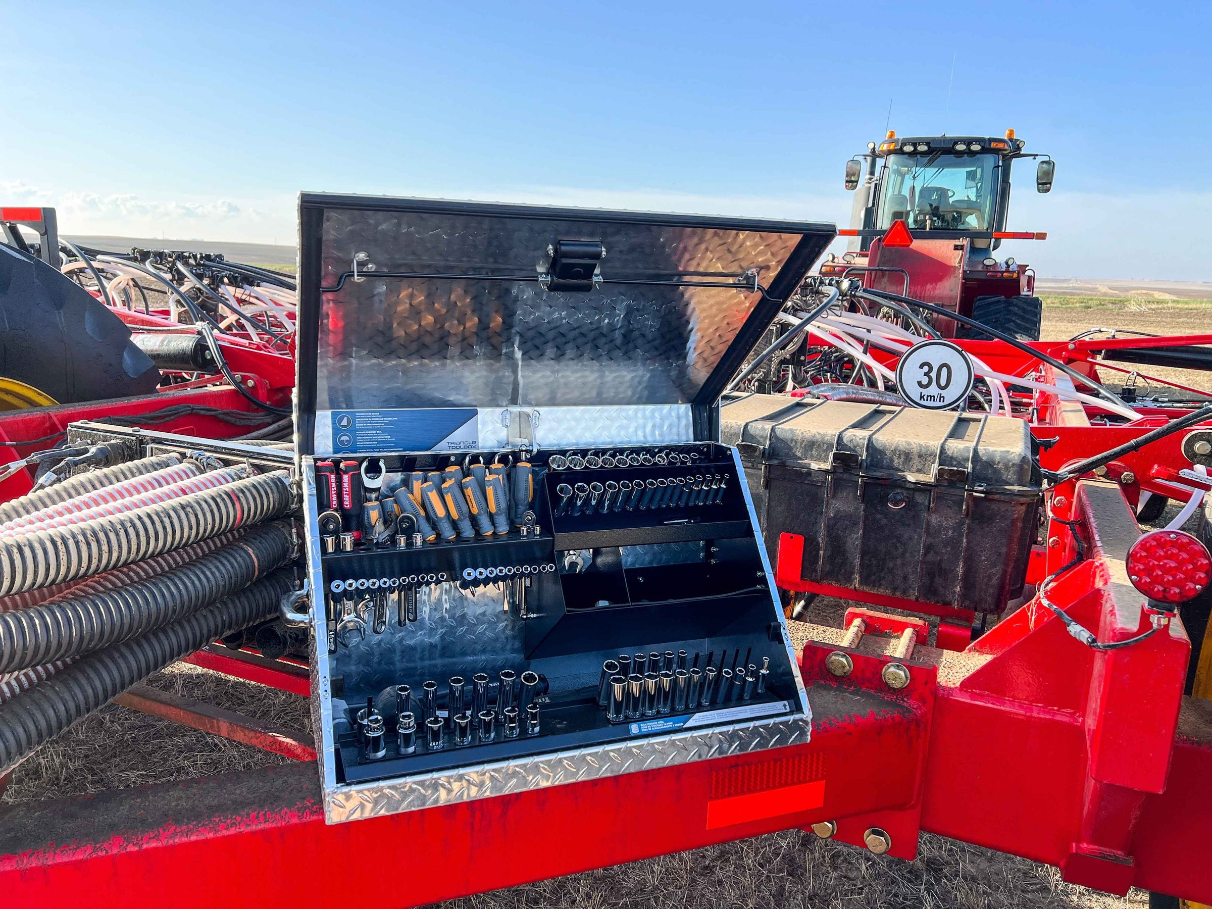 Tool chest with tools on a red agricultural machine in an open field